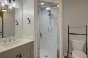 Bathroom with stacked washer / dryer, vanity, and a stall shower
