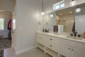 Full bathroom with double vanity, tiled shower, healthy amount of natural light, and tile patterned flooring