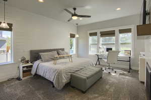 Bedroom with dark carpet, recessed lighting, an office area, wood walls, and a ceiling fan