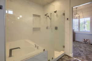 Full bathroom featuring a stall shower, a garden tub, and a chandelier
