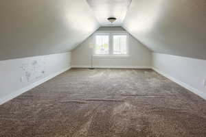 Additional living space with a textured ceiling, lofted ceiling, and carpet flooring