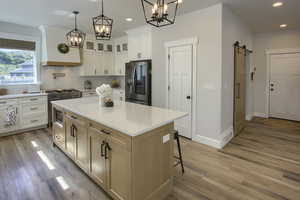 Kitchen featuring appliances with stainless steel finishes, a chandelier, recessed lighting, light wood-style floors, and a barn door