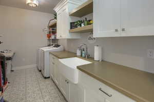 Laundry area with washer and clothes dryer, cabinet space, and light tile patterned floors