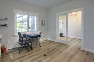 Office area with a chandelier and light wood-style flooring