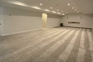Finished below grade area featuring light colored carpet and recessed lighting