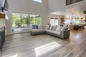 Living room with plenty of natural light, light wood-type flooring, and a high ceiling