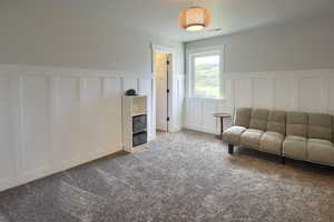 Living area with a decorative wall, a wainscoted wall, and carpet flooring