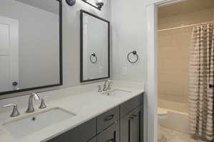 Bathroom featuring double vanity and shower / bath combo with shower curtain