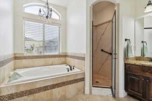 Full bath with a bath, vanity, a marble finish shower, a chandelier, and tile patterned floors