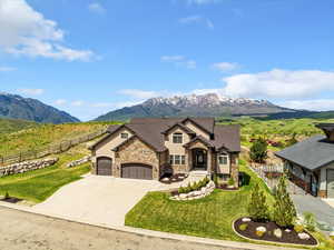 View of front of house featuring stone siding, a mountain view, a garage, concrete driveway, and stucco siding