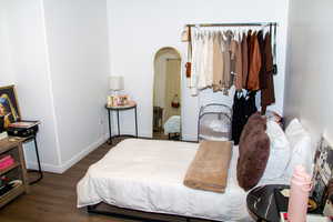 Bedroom featuring wood finished floors and arched walkways