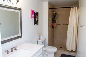 Full bath featuring vanity, tiled shower, and tile patterned flooring