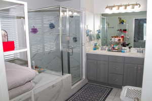 Full bathroom with a shower stall, double vanity, tile patterned flooring, and a tub