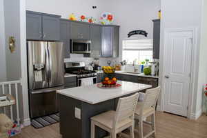 Kitchen with appliances with stainless steel finishes, light wood finished floors, decorative backsplash, a breakfast bar area, and light countertops
