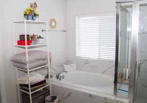 Bathroom featuring a garden tub and a shower with door