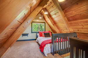 Carpeted bedroom with wooden ceiling and lofted ceiling