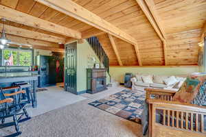 Living area featuring a wooden ceiling with exposed beams, light colored carpet, and light tile patterned floors