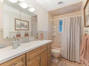 Bathroom featuring vanity, wood finished floors, and shower / bathtub combination with curtain