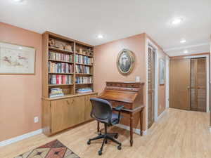 Office area with light wood-style flooring and recessed lighting