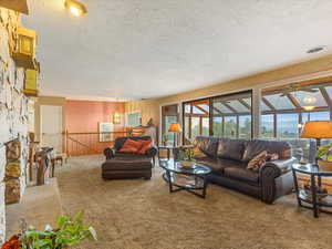 Living area with carpet flooring, a textured ceiling, ceiling fan, and a chandelier