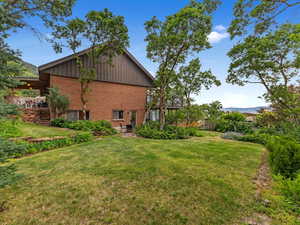 View of home's exterior with brick siding, board and batten siding, a lawn, and a patio