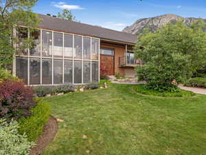 Back of house with a yard, a mountain view, and brick siding