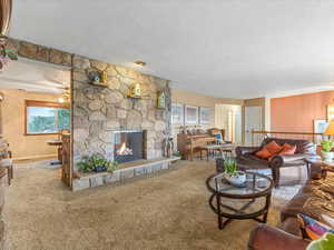Carpeted living room with a textured ceiling and a stone fireplace