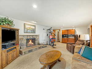 Living room featuring light carpet, a stone fireplace, and recessed lighting