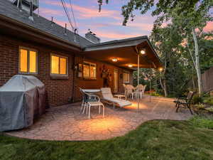 Patio terrace at dusk featuring a patio, a grill, and a lawn