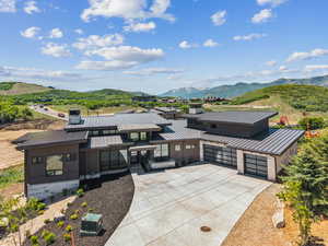 View of front facade featuring a standing seam roof, concrete driveway, a garage, and a mountain view