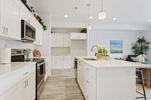 Kitchen with stainless steel appliances, light wood-style floors, a breakfast bar area, light countertops, and recessed lighting