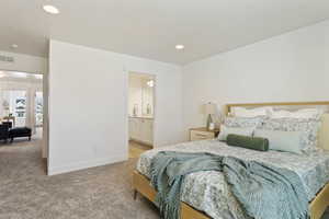 Bedroom with light colored carpet, recessed lighting, and ensuite bathroom