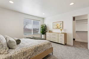 Bedroom featuring light colored carpet, recessed lighting, and a walk in closet