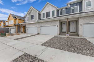 View of front of home featuring board and batten siding, an attached garage, driveway, brick siding, and a residential view