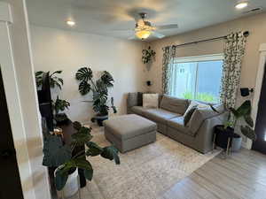Living area with a ceiling fan, wood finished floors, and a textured ceiling