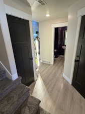 Foyer with stairway, light wood finished floors, and a textured ceiling