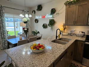 Kitchen featuring stainless steel appliances, light stone counters, wood finished floors, decorative light fixtures, and a peninsula