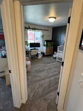 Hall featuring carpet flooring, a textured ceiling, and an office area