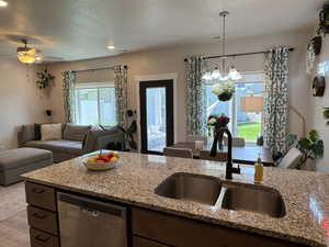 Kitchen with dishwasher, open floor plan, light wood-type flooring, light stone counters, and plenty of natural light
