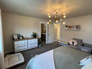 Bedroom with a chandelier, dark colored carpet, and a textured ceiling