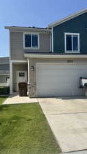 Traditional home with an attached garage, stone siding, driveway, and a front lawn