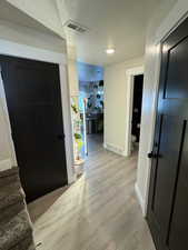 Foyer entrance with a textured ceiling, light wood finished floors, and stairway