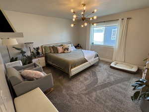 Carpeted bedroom with a chandelier and a textured ceiling