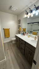 Full bathroom with wood finished floors, double vanity, a stall shower, and a textured ceiling