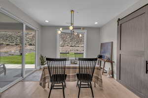 Dining room with light wood-type flooring, healthy amount of natural light, a barn door, and recessed lighting