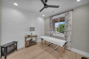Living area featuring a wood stove, ceiling fan, light wood-style flooring, recessed lighting, and wood walls