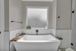 Bathroom with a soaking tub and a wainscoted wall
