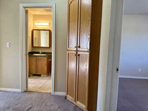 Hall with light colored carpet and light tile patterned flooring built-in storage cabinet