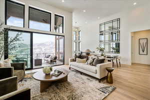 Living area with a towering ceiling, a mountain view, light wood-type flooring, a chandelier, and recessed lighting