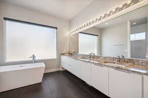Bathroom featuring double vanity, a soaking tub, tiled shower, and recessed lighting